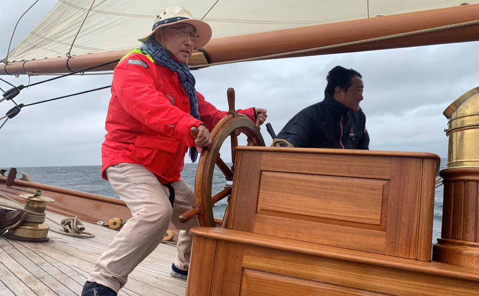 写真：船の舵をとる代表　渡邊曻